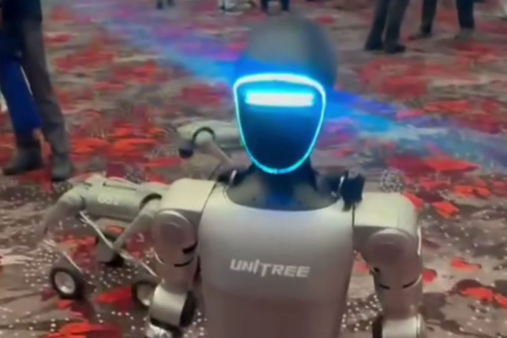 Ben, humanoider Roboter, in einer Messehalle mit Besuchern im Hintergrund.